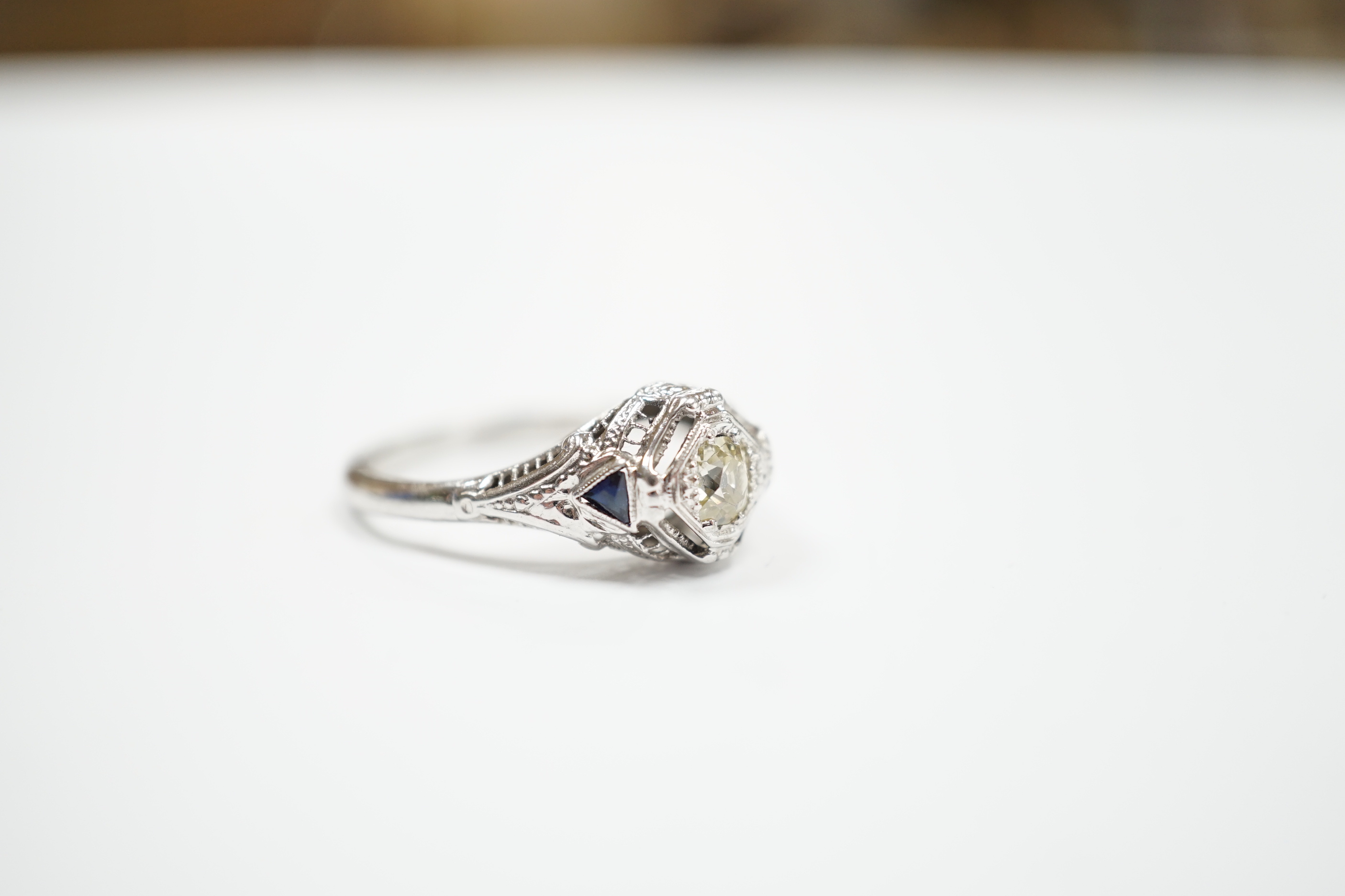 An 18ct and single stone diamond set ring, with two stone triangular sapphire set shoulders, size P, gross weight 3.1 grams.